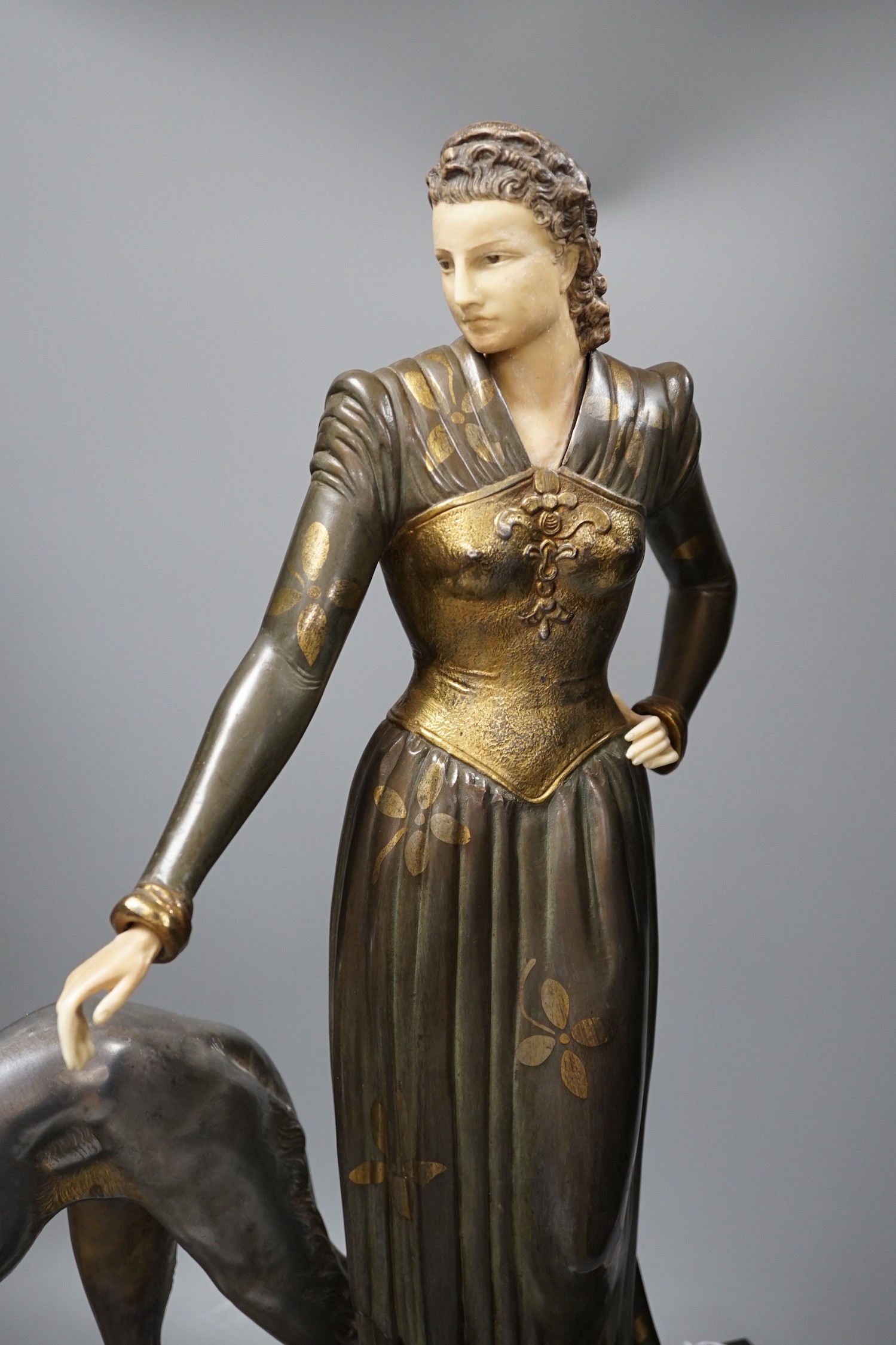 An Art Deco spelter and composition figure of a lady and a hound, signed Menneville, 57 cms high